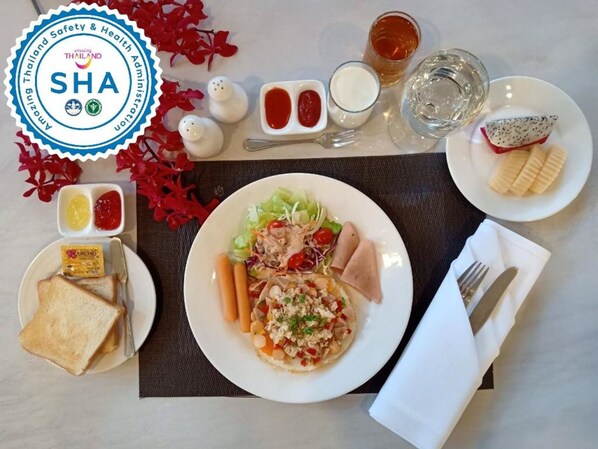 Una mesa dispuesta con ensalada, pan, salsas y un vaso de agua.