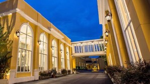 L'ingresso di un hotel con facciata gialla, ampie finestre ad arco e una tettoia.
