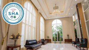 Un'ampia hall con un lampadario, divani in pelle e ampie finestre che offrono vista sul verde.