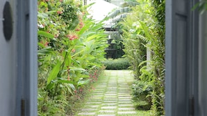 A pathway leading through a lush garden with a variety of plants and a stone-tiled path. - The Hen Hua Hin Private Beach Villa (Hua Hin)
