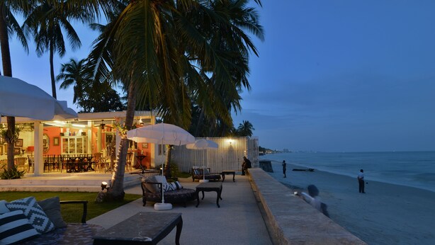 A beachfront patio with outdoor seating, palm trees, and a view of the ocean. - The Hen Hua Hin Private Beach Villa (Hua Hin)