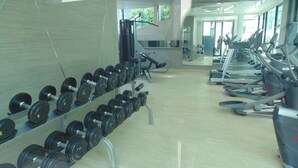A gym with treadmills, elliptical machines, and a rack of dumbbells. - Acqua Condominium (Pattaya)