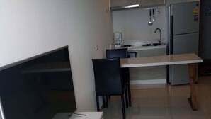 A modern kitchen with a flat-screen TV, a coffee maker, and a refrigerator. - Acqua Condominium (Pattaya)