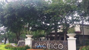 A sign for Pacifico with a stone wall and potted plants. - Pacifico Paradise Condo, Playas del Coco, Guanacaste, Costa Rica (Coco)