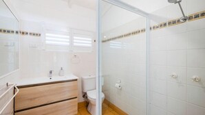 A bathroom with a toilet, sink, and shower. - Captains Bridge Wooli (Wooli)