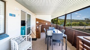 A balcony with a table and chairs, a sofa, and a sign indicating "Captain's Bridge". - Captains Bridge Wooli (Wooli)