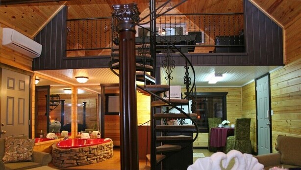 Ein gemütliches Interieur mit einer Wendeltreppe, Holzwänden und einem Kamin aus Stein.