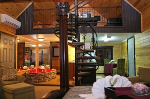 A cozy interior with a spiral staircase, wooden walls, and a stone fireplace.