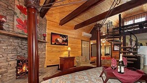 Ein gemütliches Zimmer mit einem Bett, einem Kamin, einem Gemälde und einer Wendeltreppe.