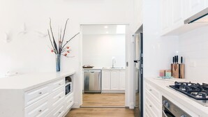 Una cocina moderna con armarios blancos, electrodomésticos de acero inoxidable y suelo de madera.