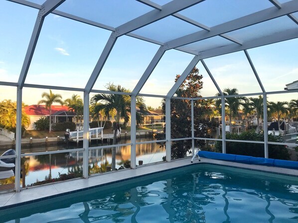 A pool area with a clear view of the surrounding landscape, including palm trees and a body of water.