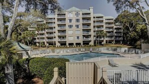 A multi-story hotel with a swimming pool surrounded by lounge chairs and a deck. - Fully Updated Kitchen and Bathrooms with an Ocean View! (Hilton Head)