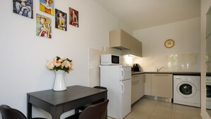 A modern kitchen with a dining area, including a table with chairs, a microwave, a coffee maker, and a washing machine. - JP1 - apartman for 2 (Vrbnik)