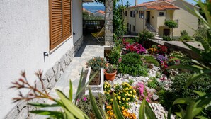 A courtyard with a stone pathway, potted plants, and a view of a mountain. - JP1 - apartman for 2 (Vrbnik)