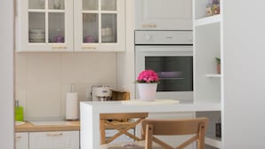A kitchen with white cabinets, a built-in oven, and a wooden table with a chair.