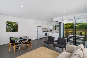 Un espacio habitable moderno con comedor, cocina y un balcón con vistas a zonas verdes.