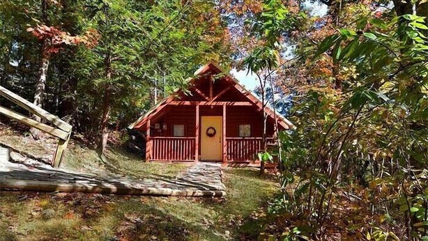 Eine Holzhütte mit Veranda und einer Tür, die mit einem Kranz geschmückt ist.
