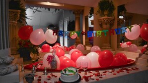 Ein luxuriöser Raum mit festlicher Dekoration, darunter ein Kuchen, Luftballons und ein „Happy Birthday“-Banner.