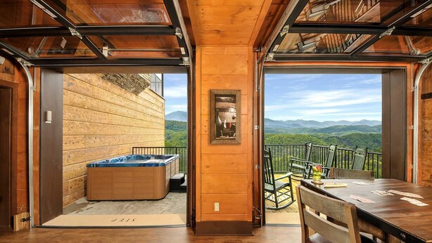 Un interior de madera con una bañera de hidromasaje, una mesa de comedor y vistas a las montañas.