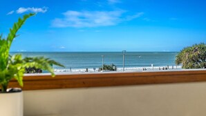 A beach view with a clear sky, a wooden railing, and a sign indicating parking.