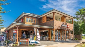 A two-story building with a Quiksilver store, a board hire sign, and surfboards outside.