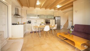 Una cocina moderna con armarios blancos, una mesa de comedor de madera y un sofá púrpura.