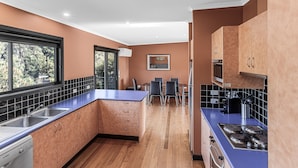 Une cuisine moderne avec des meubles en bois, un plan de travail bleu et un coin repas comprenant des chaises et une table.