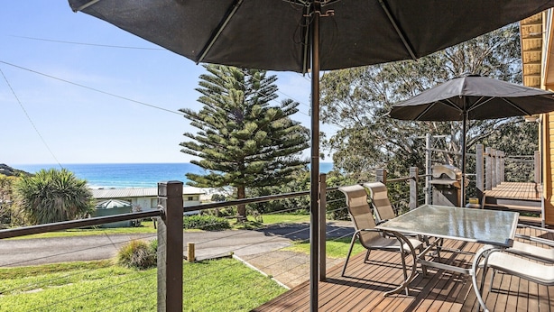 Une terrasse avec une table et des chaises, offrant une vue sur la côte.