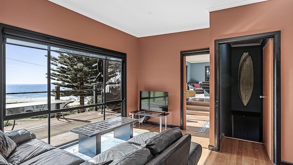 Una sala de estar moderna con un amplio ventanal que da a una terraza, un sofá, una mesa de centro y un televisor.