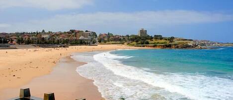 A beach resort with a swimming pool, sandy beach, and ocean view.