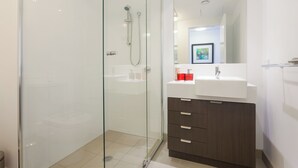 A modern bathroom with a glass-enclosed shower, a white sink, and dark wooden cabinets. - Executive 2BR Fortitude Valley apartment with pool and views (Fortitude Valley)