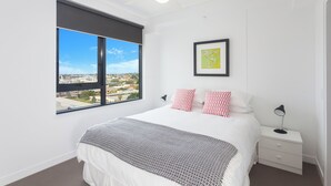 A bedroom with a large window, a bed, a nightstand, and a ceiling fan. - Executive 2BR Fortitude Valley apartment with pool and views (Fortitude Valley)