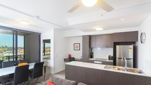 A modern kitchen with a central island, a dining area with a table and chairs, and a view through large windows. - Executive 2BR Fortitude Valley apartment with pool and views (Fortitude Valley)