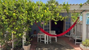 A covered patio area with a hammock, outdoor furniture, and potted plants. - Charming Poolside Studio with Private Porch in Curaçao (Willemstad)