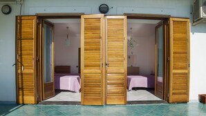Una stanza con due letti, porte scorrevoli in legno e pavimento piastrellato.
