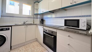 A compact kitchen with white cabinets, a microwave, a coffee maker, and a dishwasher. - Agi La Pinta 41 Apartamento for rent in Roses Girona. (Rosas / Roses)