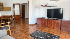 A living room with a TV, wooden furniture, and a dining area. - Agi La Pinta 41 Apartamento for rent in Roses Girona. (Rosas / Roses)