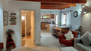A spacious living area with a red sofa, a kitchen in the background, and a wooden ceiling.