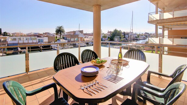 A dining area with a table set for four, overlooking a marina with boats and a clear view of the cityscape.