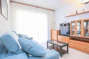 Relax in this stylish living room with a sofa, coffee table, and TV, surrounded by natural light and a large window.