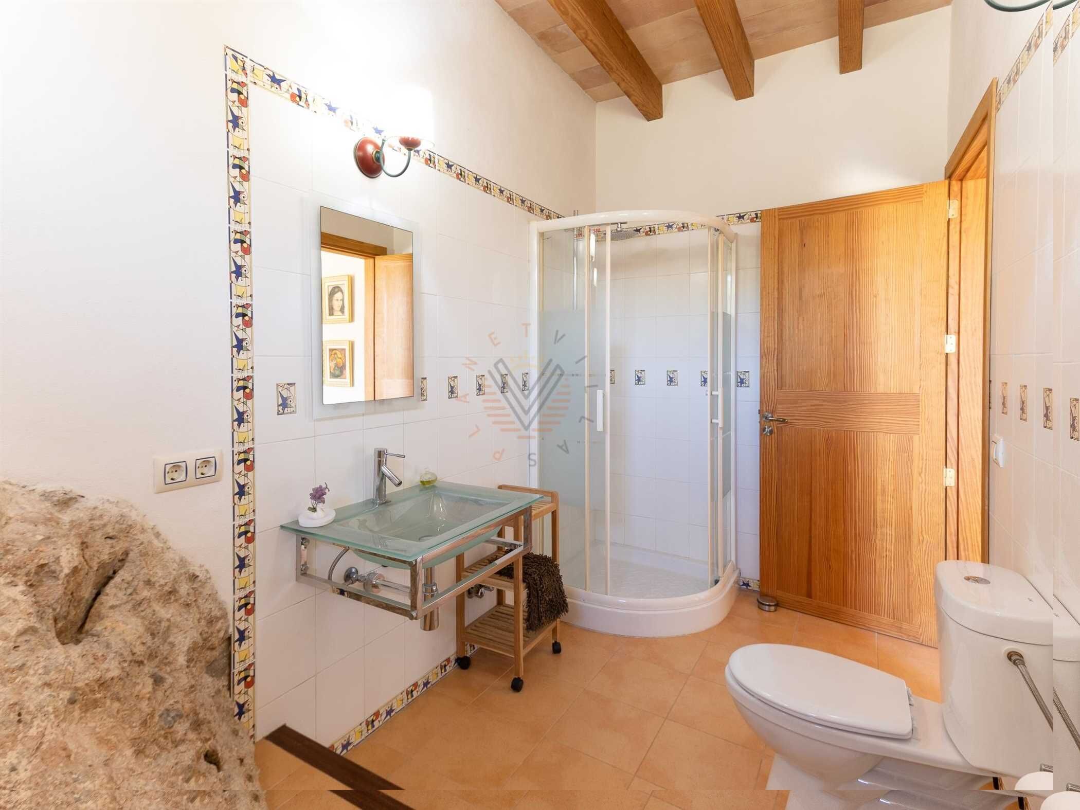 A bathroom with a glass sink, a shower, and a wooden door.