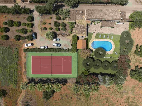 An aerial view of a residential property with a tennis court, a swimming pool, and a parking area. - Cas Home, villa with tennis court and private pool (Buger)