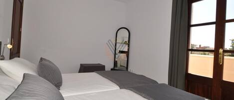 Habitación de hotel con una cama grande, un escritorio, un espejo y una ventana con cortinas.