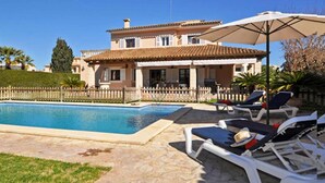 Uma villa com piscina, área de estar ao ar livre e jardim cercado.