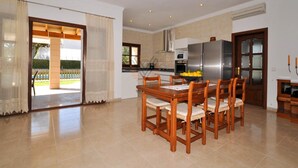Uma cozinha espaçosa com área de jantar, geladeira e janela com vista para um jardim.