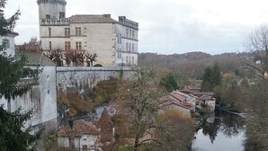 Un edificio histórico con una torre, rodeado por un foso y construcciones más pequeñas.