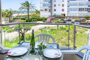 Un balcone con un tavolo apparecchiato per due, con vista sulla spiaggia e un'area parcheggio.
