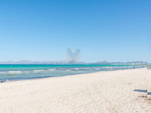 Una spiaggia con acque cristalline turchesi, una costa sabbiosa e montagne in lontananza.