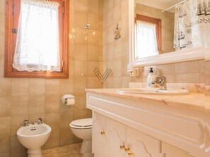 Un bagno con servizi igienici, bidet e lavandino, tutto in bianco.