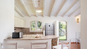 A kitchen with a granite countertop, white cabinets, a built-in refrigerator, and a stone accent wall.
